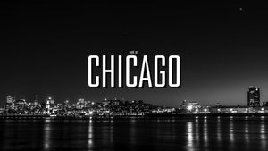Chicago wall art title over a black and white waterfront cityscape with night lights reflected in the water.