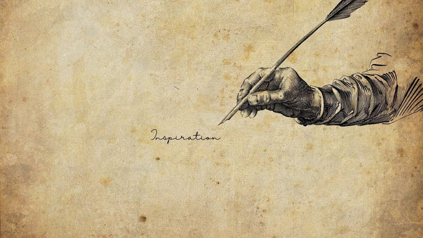 Vintage illustration of a hand holding a quill above the word Inspiration