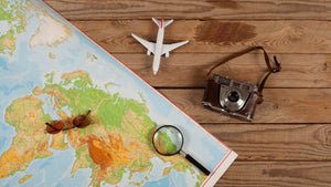 World map, vintage camera, sunglasses and airplane on a table, representing travel photography and exploring place