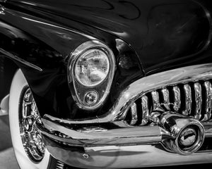 Rounded Buick headlight above vertical grille bars and a reflective chrome bumper