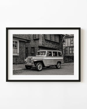 1953 Willys Jeep wagon outside a shingled house in black and white