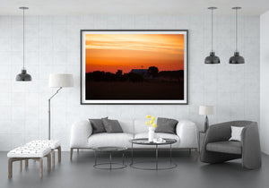 Warm bands of orange and gold light above a quiet American farm.