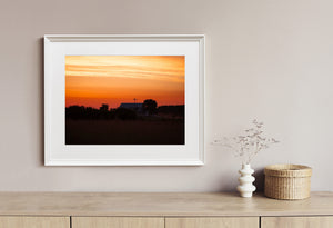 Dark farmland and a small farmhouse beneath the first light of dawn.