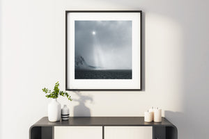 A bright point of sun over the misty Antarctic coast and dark water.