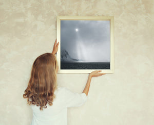 Antarctic seascape with a veiled sun, descending light and a distant snowy shore.