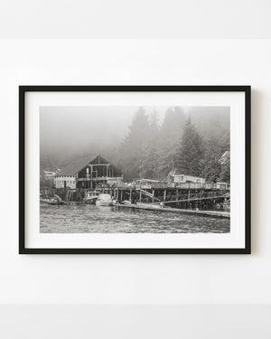 Abandoned British Columbia waterfront resort with weathered docks beneath a misty forest.