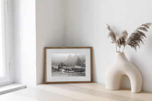 Monochrome coastal scene with worn resort buildings, docks and small boats.