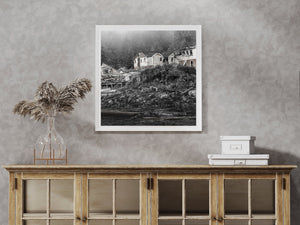 A row of deserted coastal buildings beneath misty conifers in British Columbia.