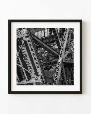 Riveted steel and cross-bracing on an abandoned Chicago industrial bridge in black and white.