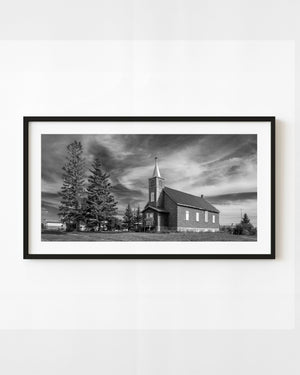 Abandoned church near Leross, Saskatchewan, beneath sweeping clouds in black and white.