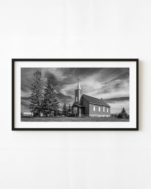 Abandoned church near Leross, Saskatchewan, beneath sweeping clouds in black and white.
