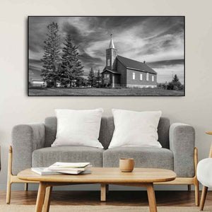 Small Saskatchewan church with boarded openings and tall trees beside it.