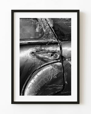 Weathered classic car door with cracked paint and cobwebs, photographed in black and white.