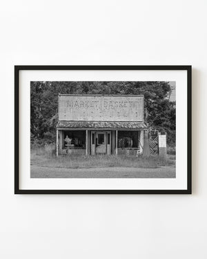 Abandoned clothing store in the American South with a faded sign, photographed in black and white.