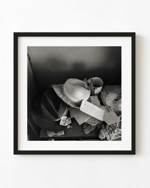 Two abandoned hats among letters and household objects in Clarence Town, Bahamas, in black and white.