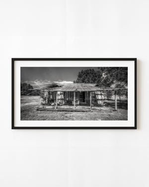 Abandoned Indiana homestead with a buckled metal roof and sagging porch in black and white.