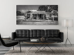 Monochrome rural house photograph with uneven doors, aged boards and rough grass.