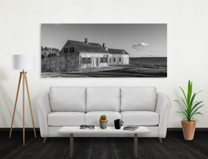 Abandoned clapboard home on the Maine coast beneath a lightly clouded sky