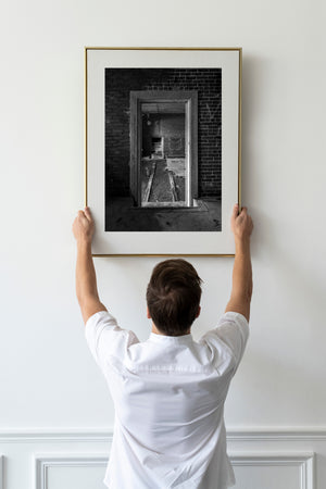 An abandoned brick interior with layered doorway moulding and a smaller opening beyond