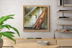 A decaying wooden boat rests almost upright beneath a concrete staircase