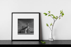 Thin clouds stretch above a deserted rural church surrounded by trees