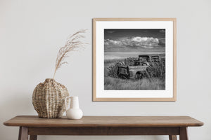 Black and white photograph of a deserted truck beside an open prairie field