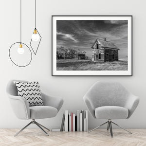 Pale worn siding catches the light on an abandoned farmhouse in open grassland