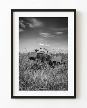 Abandoned tractor surrounded by tall Saskatchewan prairie grass in black and white.