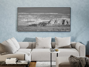 Open grass surrounds an isolated Southwest farmstead beneath a broad rocky escarpment.