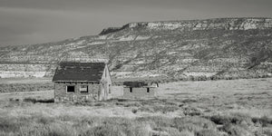 Panoramic monochrome landscape of weathered homes across an open grassy desert.