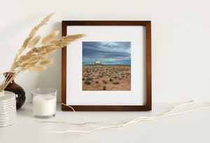 A pale schoolhouse roof contrasts with blue-grey clouds and warm desert terrain.