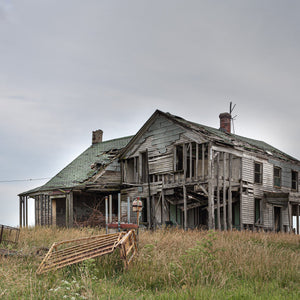 Dilapidated Indiana farmhouse surrounded by overgrown fields