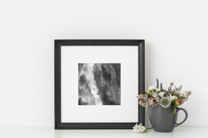 Black and white waterfall detail with bright cascades and textured mist against dark rock.
