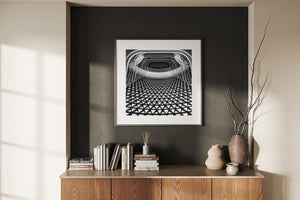 A triangular architectural grid recedes beneath rounded white layers around a dark opening.