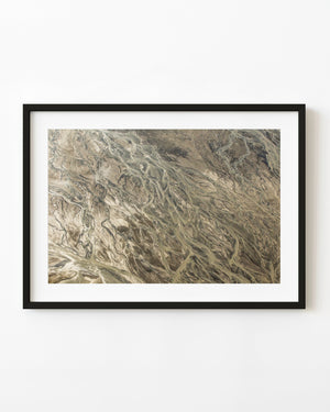 Winding channels and pale bands of earth across an Alaskan aerial landscape.