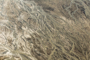 Colour aerial photograph of branching channels across muted beige, grey and brown Alaska terrain.