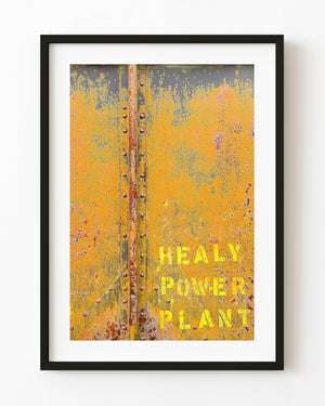 Weathered yellow and orange paint on riveted Alaska railcar panels with faded Healy Power Plant lettering.