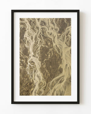 Pale tidal channels branching across brown coastal ground in an aerial Alaska photograph.