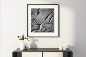 A smooth central channel curves through dark edges and finely ridged coastal sediment.