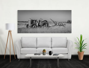 Exposed tractor engine and a large rear wheel stand above prairie grass east of Medicine Hat.