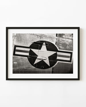 A pale American aircraft star insignia spans riveted metal in a black and white aviation detail photograph.