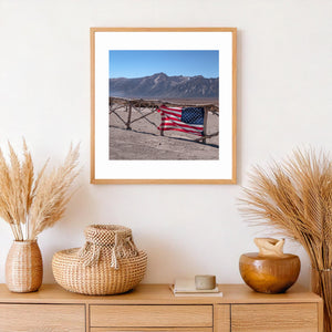 Colour memorial photograph with flag fabric, wooden rails and an open mountain landscape.