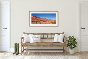 Slim poles beside the tracks punctuate an open desert panorama under clear blue sky.
