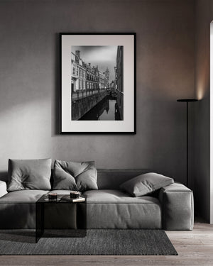 A pale sky outlines the clock tower beyond canal-side buildings and their inverted reflections.