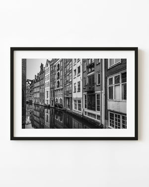 A close row of Amsterdam canal houses and their reflections fill a black and white architectural photograph.