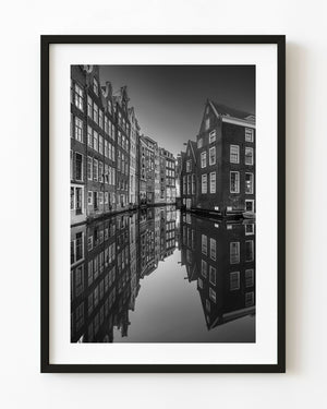 Narrow Amsterdam canal houses and clear reflections photographed in black and white.