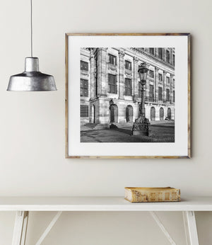 Morning light on palace windows and carved stone behind a tall Amsterdam streetlamp.