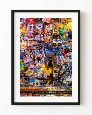 Colourful Amsterdam sticker wall with a warm bottle lamp among overlapping labels and writing.