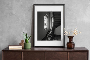 Wooden steps curving beside two bright windows in a historic Amsterdam interior.