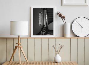 Amsterdam staircase with a curved wooden edge connecting two flights beside bright windows.